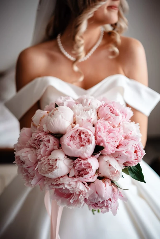 Bride holding a full bouquet of dusty pink peonies