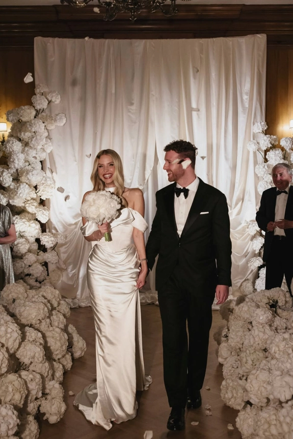 Leonie Hanne and Alexander Galievsky walking through a white floral wedding ceremony