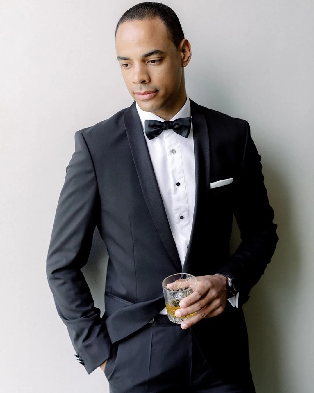 Groom photographed in a black shawl-collar tuxedo and bow tie