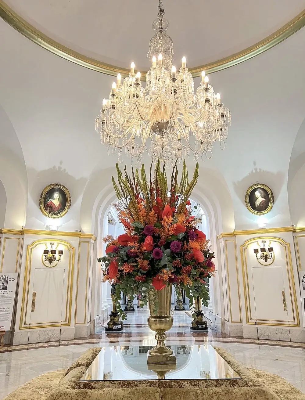 Crystal chandelier and grand floral arrangement in a gold urn