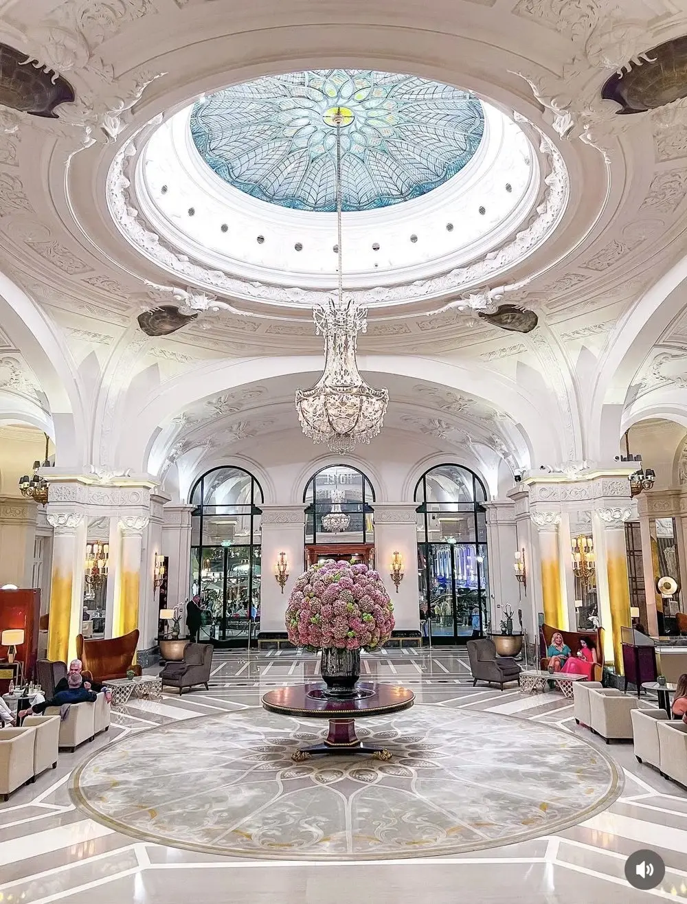 Grand palace hotel lobby beneath a stained-glass dome and chandelier