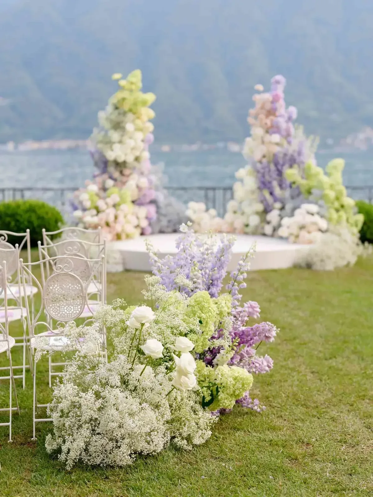 Lakefront ceremony with meadow-style pastel floral installations